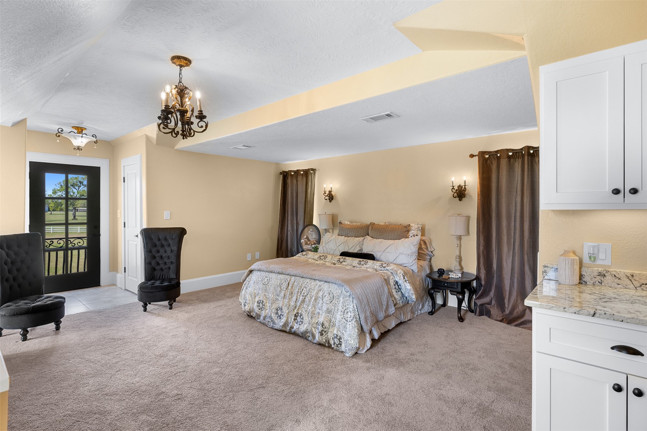 29500 Skymac Ranch Road Hempstead, TX 77445 - Photo 38 of 50 a spacious bedroom with a bed and a chandelier