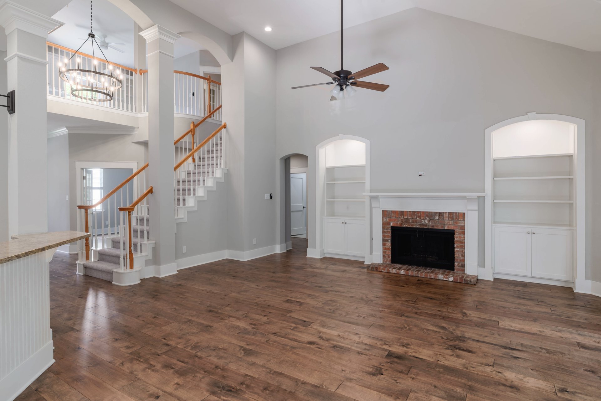 5512 Ballenton Lane Austin, TX 78739 - Photo 11 of 40 A spacious great room showcases soaring vaulted ceilings and a classic brick fireplace, framed by elegant built-in shelving.