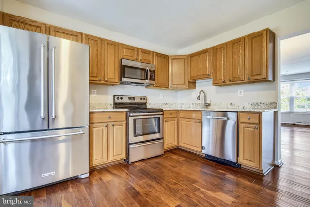 a kitchen with white cabinets stainless steel appliances and wooden floor