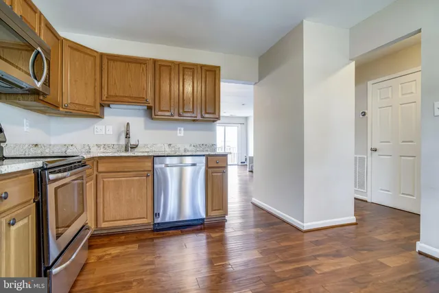 a kitchen with granite countertop wooden floors stainless steel appliances and cabinets