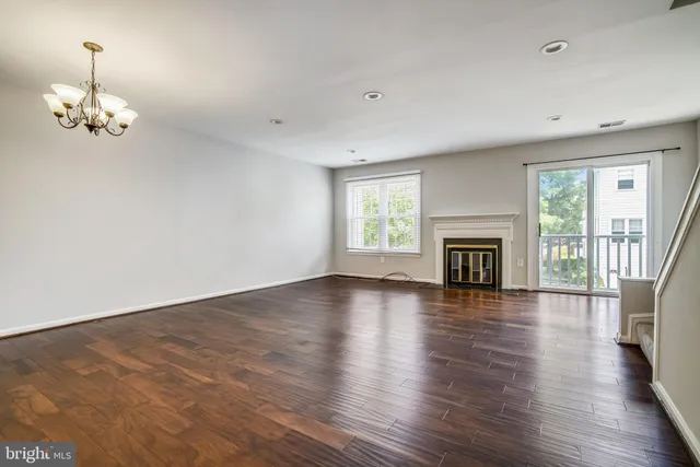 an empty room with wooden floor fireplace and windows