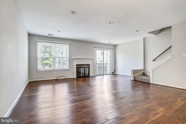 an empty room with wooden floor fireplace and windows