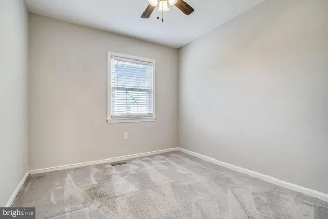 an empty room with a window and a chandelier fan