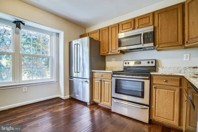a kitchen with stainless steel appliances granite countertop a stove microwave refrigerator and cabinets