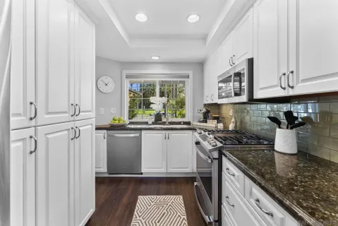 a kitchen with stainless steel appliances granite countertop a stove a sink and a white cabinets