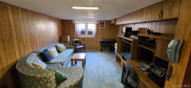 a living room with furniture a flat screen tv and a refrigerator