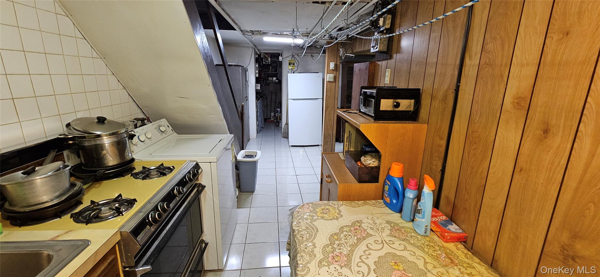 78-54 75th Street Queens, NY 11385 - Photo 17 of 31 Kitchen with white appliances, light tile patterned flooring, light countertops, and independent washer and dryer