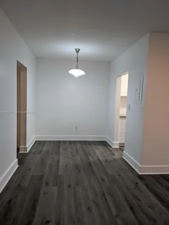 an empty room with wooden floor and sink