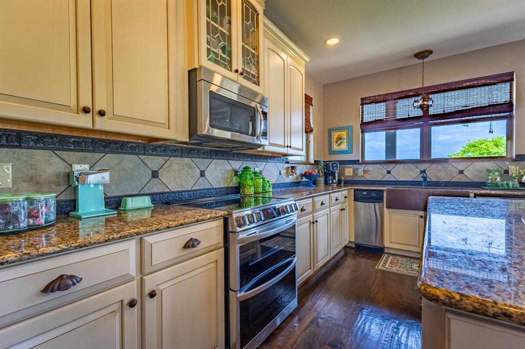 7060 Hells Gate Loop Strawn, TX 76475 - Photo 6 of 40 a kitchen with stainless steel appliances granite countertop a stove and cabinets