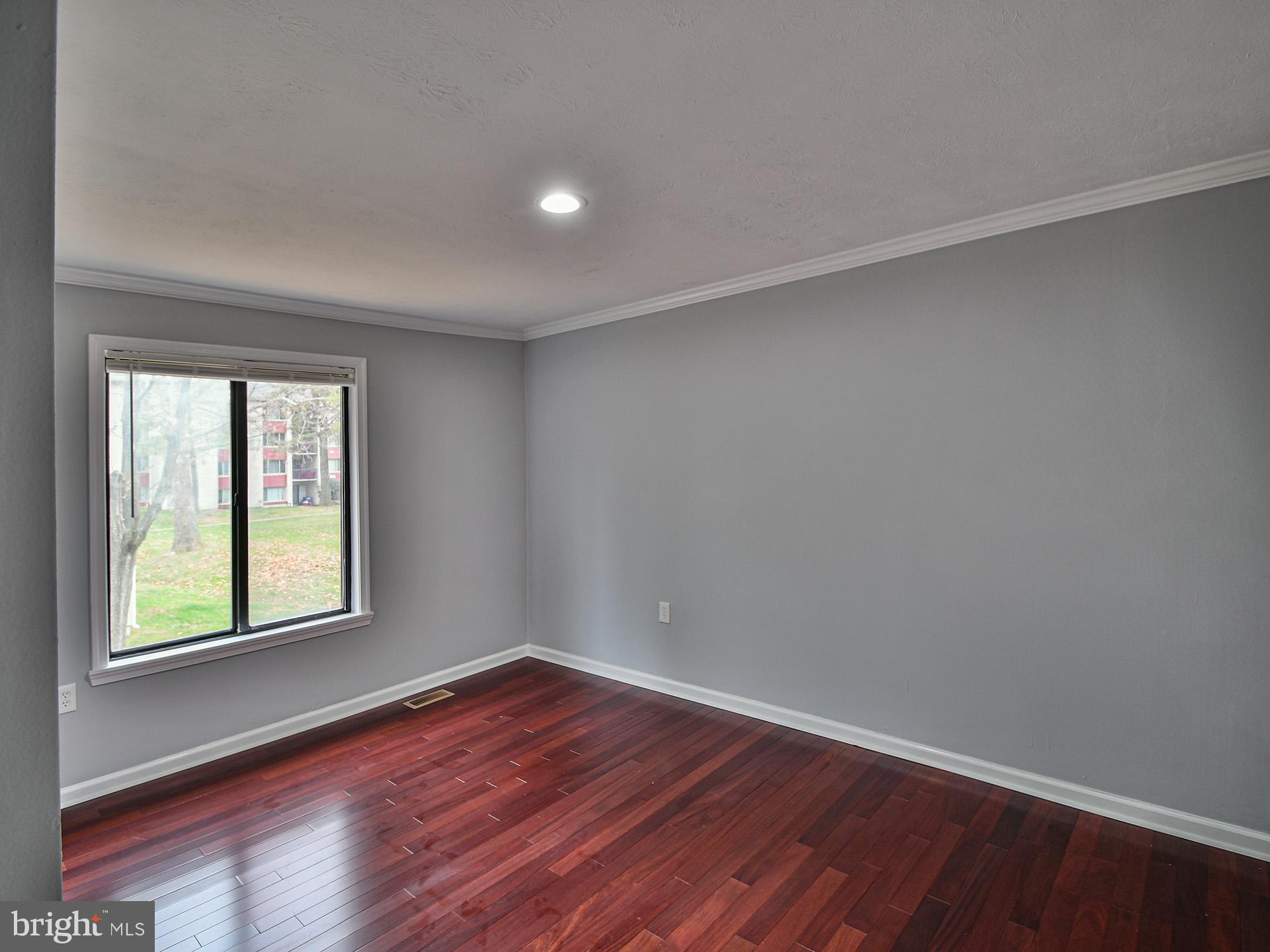 3511 Castle Way, Unit 312 Silver Spring, MD 20904 - Photo 20 of 34 a view of an empty room with wooden floor and a window