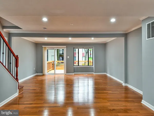 a view of an empty room with window and wooden floor