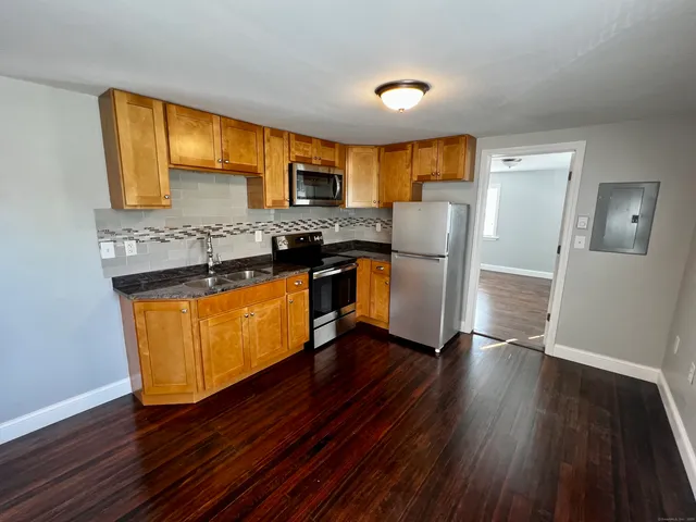 a kitchen with stainless steel appliances granite countertop wooden floors and a stove