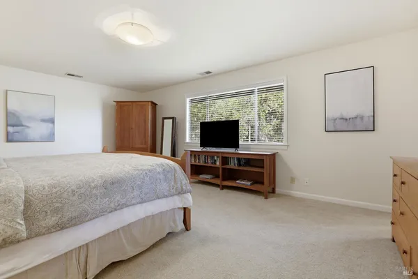 a spacious bedroom with a bed and a flat screen tv