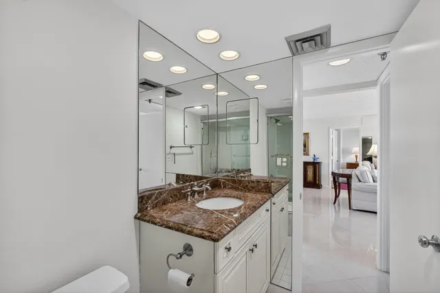 a bathroom with a granite countertop sink a mirror and a shower