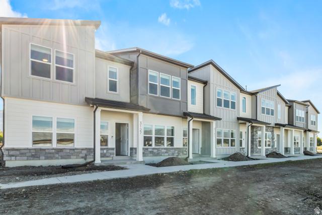 2995 South 265th Street West, Unit 752 Logan, UT 84321 - Photo 1 of 21 Modern townhome exterior featuring multi-toned siding, stone veneer accents, multiple large windows, a covered entry, and a concrete walkway