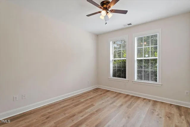 an empty room with a window and a fan