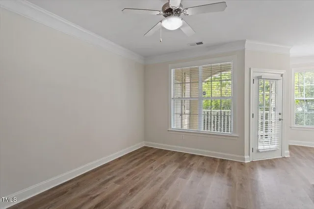a view of an empty room with a window and wooden floor