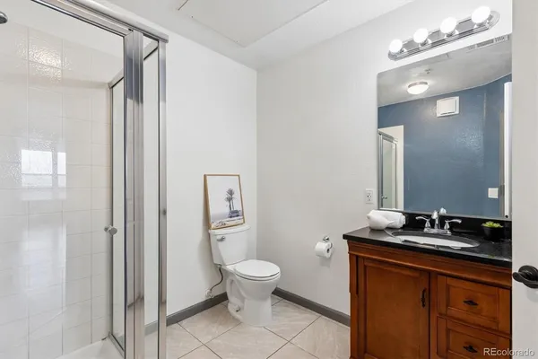 a spacious bathroom with a granite countertop sink a toilet a mirror and a shower
