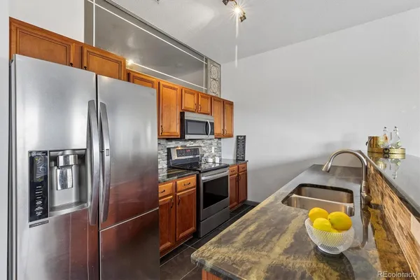 a kitchen with stainless steel appliances granite countertop a sink a stove and refrigerator