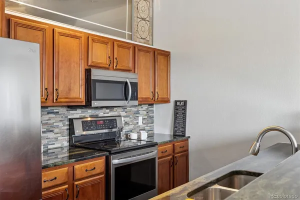 a kitchen with stainless steel appliances granite countertop a stove a sink and a microwave