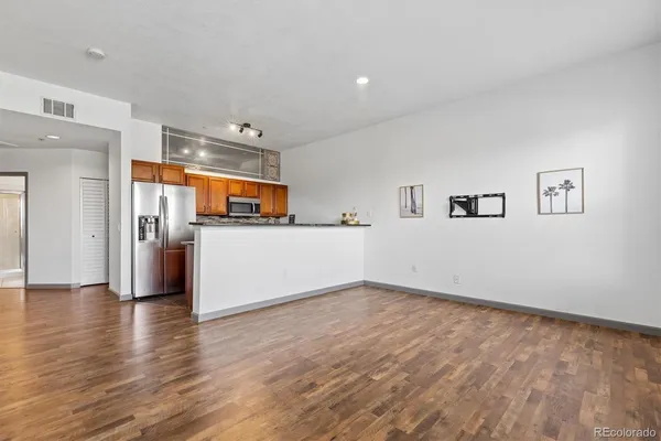 a view of a big room with wooden floor and a kitchen