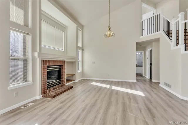 a view of an empty room with wooden floor fireplace and a window