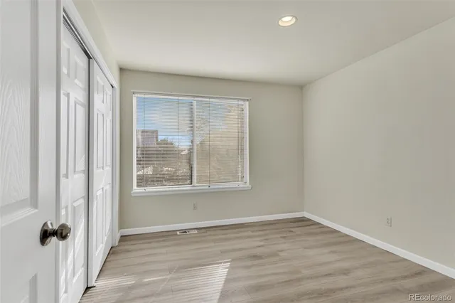 an empty room with wooden floor and windows