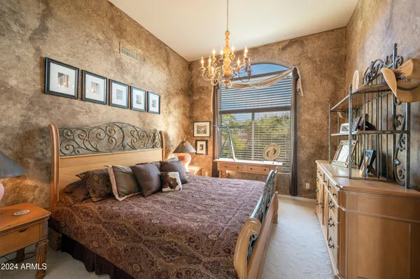 a bedroom with a bed and chair with the outer view