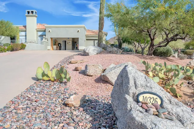 a pathway of a house with potted plants and big trees