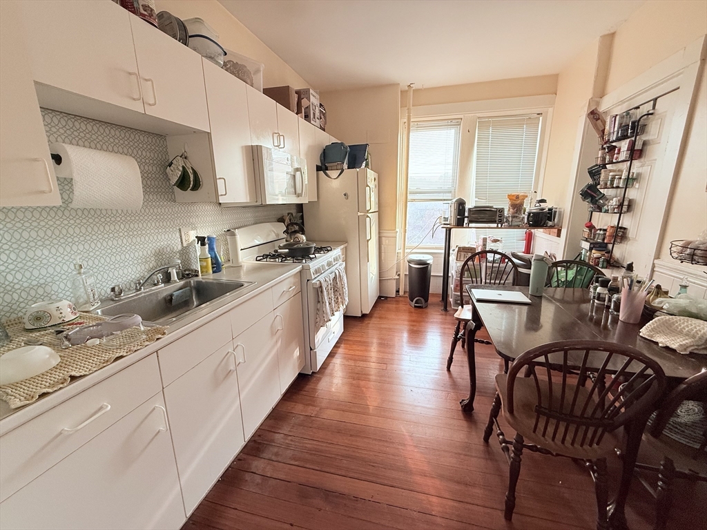 a kitchen with stainless steel appliances kitchen island granite countertop a table chairs stove and cabinets
