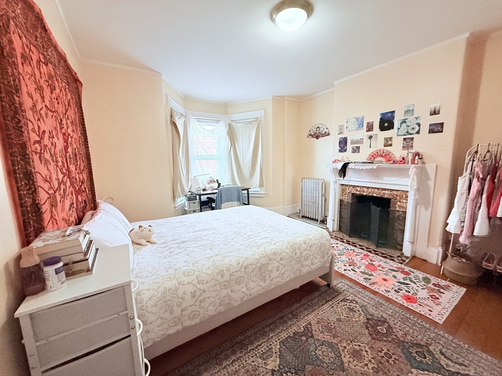 220-224 Washington Street, Unit 7A Brookline, MA 02445 - Photo 6 of 9 a bedroom with a bed and a fireplace with wooden floor