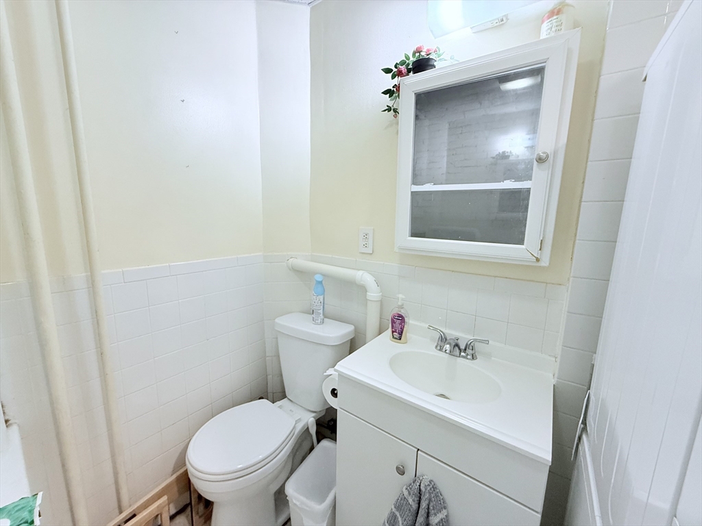 220-224 Washington Street, Unit 7A Brookline, MA 02445 - Photo 9 of 9 a bathroom with a sink mirror and toilet