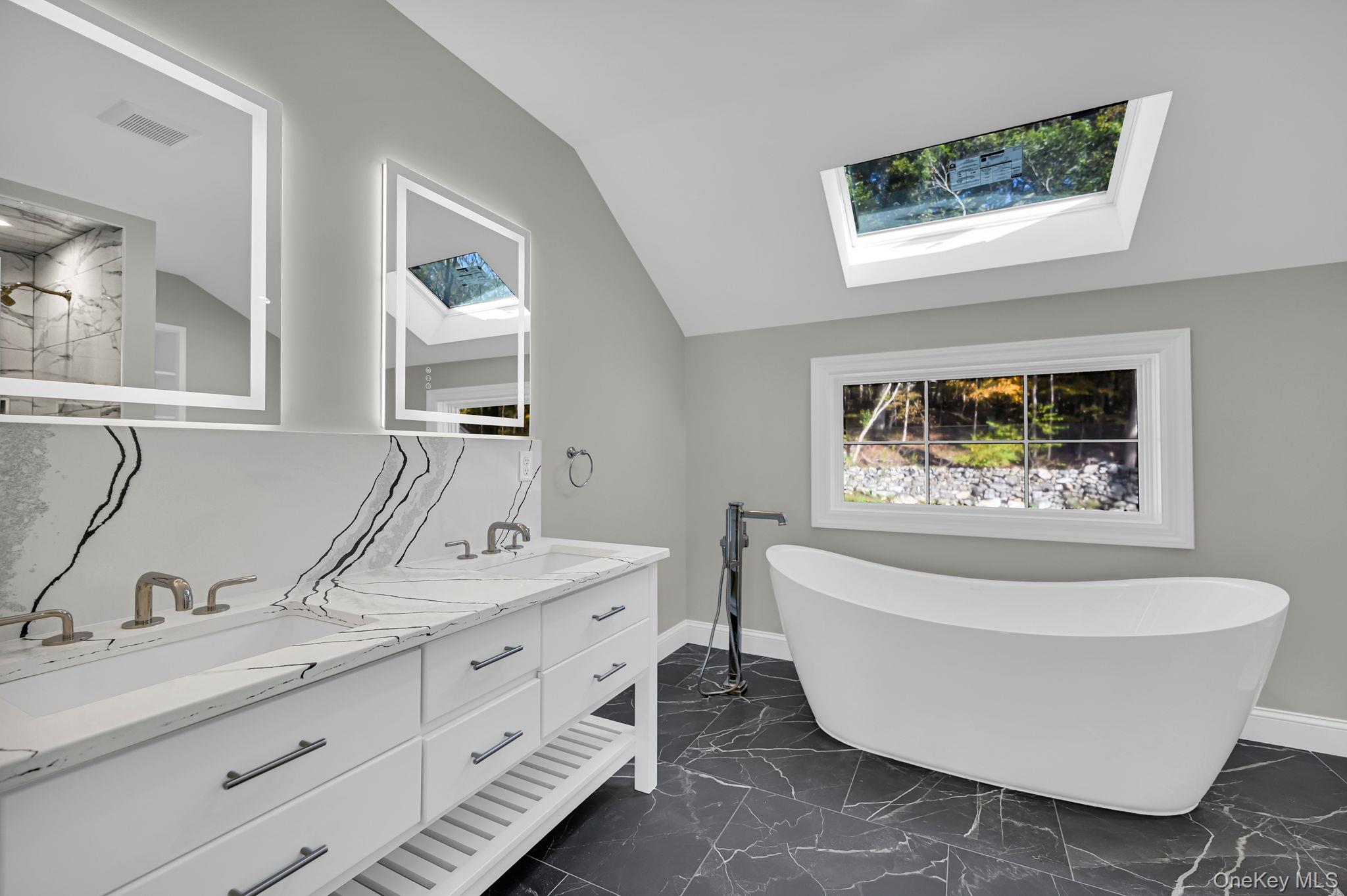 170 Brimstone Road Patterson, NY 12563 - Photo 27 of 48 Bathroom featuring vaulted ceiling, a freestanding tub, a skylight, dark marble finish flooring, and double vanity