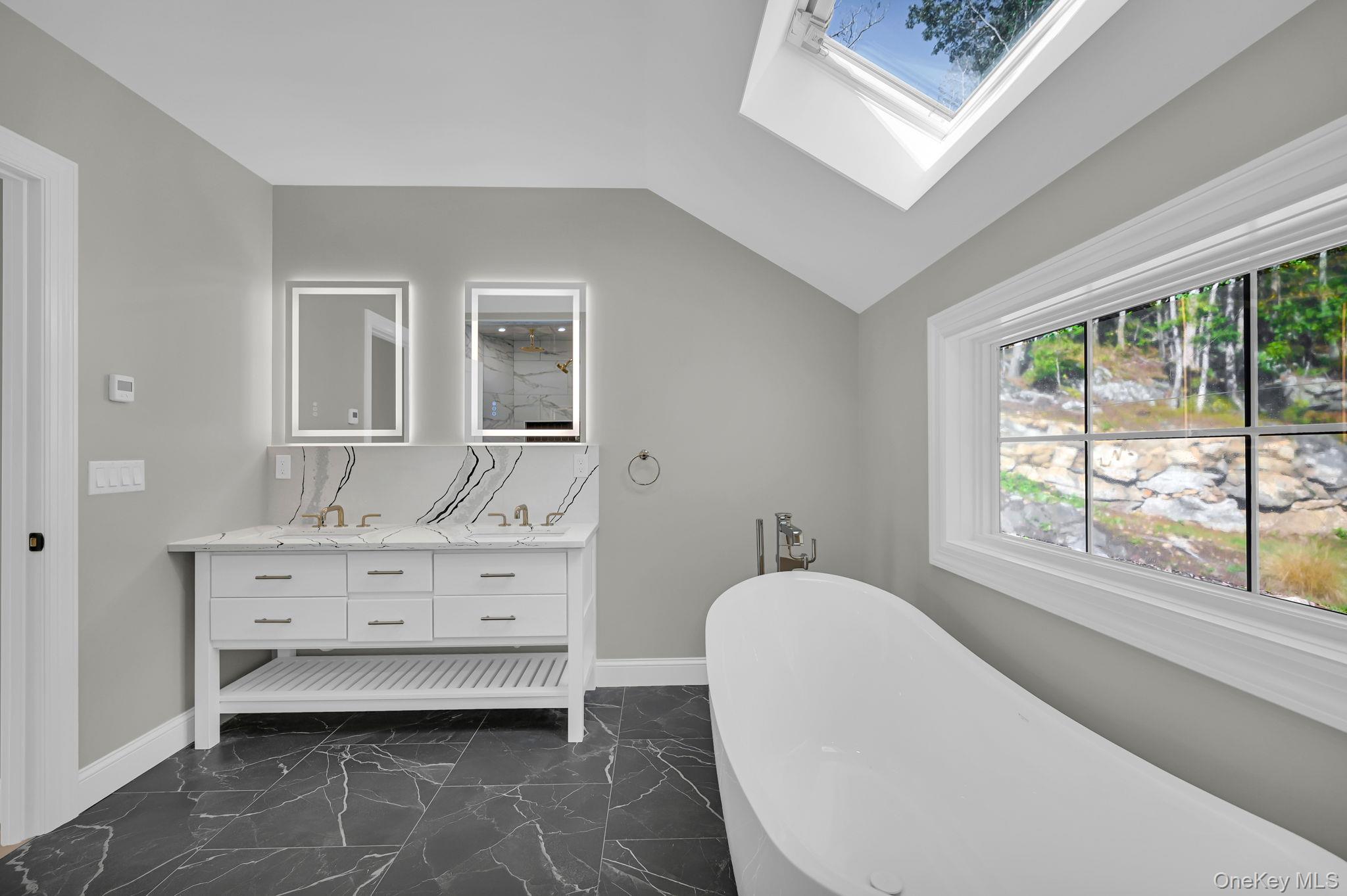 170 Brimstone Road Patterson, NY 12563 - Photo 28 of 48 Full bath with a freestanding bath, double vanity, a skylight, dark marble finish floors, and vaulted ceiling