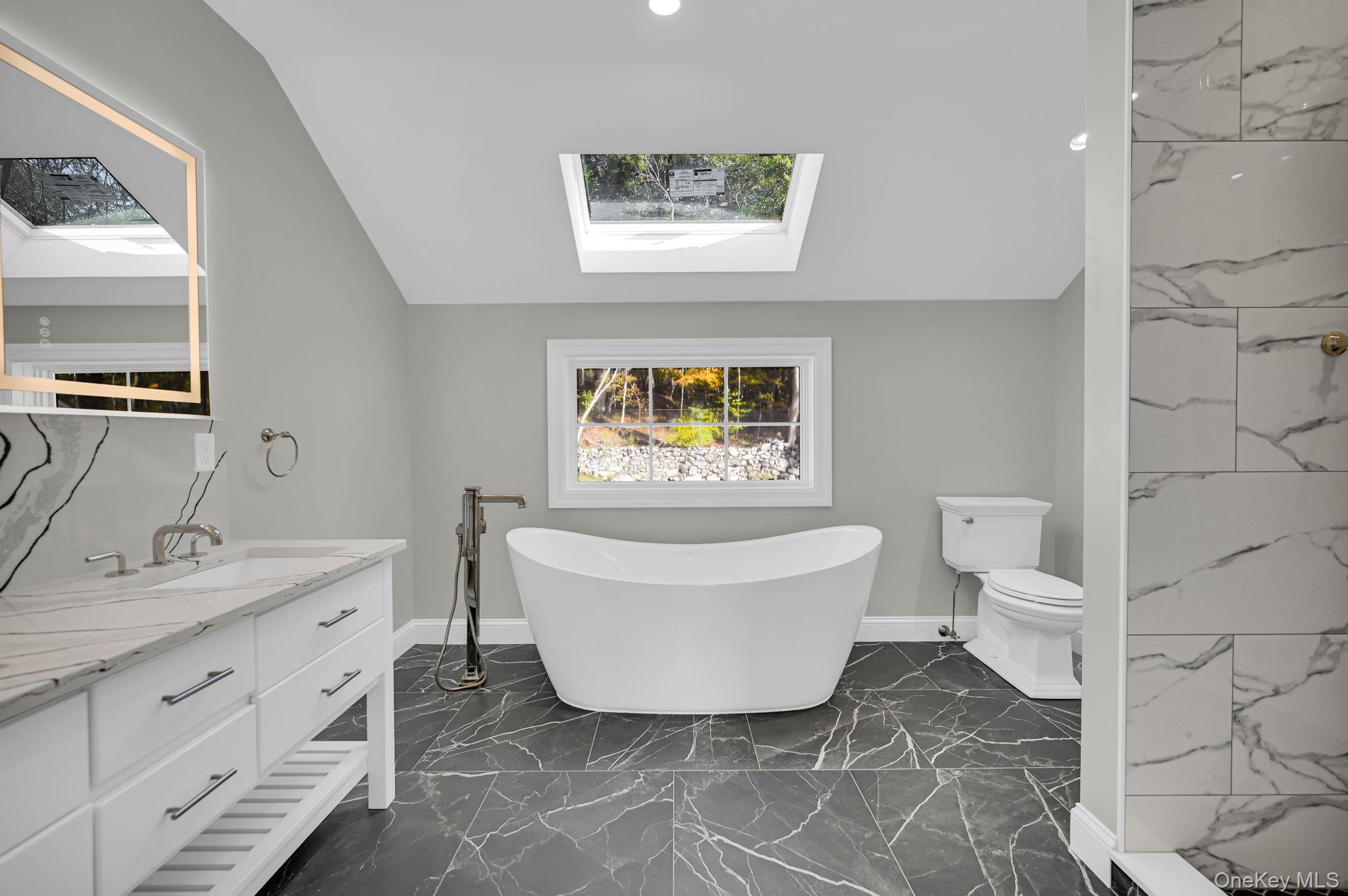 170 Brimstone Road Patterson, NY 12563 - Photo 30 of 48 Full bath featuring a skylight, vanity, a freestanding tub, lofted ceiling, and dark marble finish floors