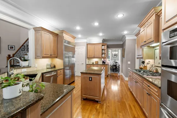 a kitchen with stainless steel appliances granite countertop a refrigerator a stove and a sink with wooden floor