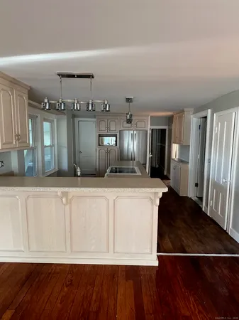 a view of a kitchen with kitchen island wooden floor and refrigerator