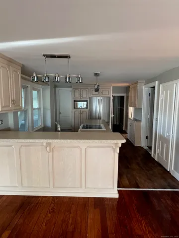 a view of a kitchen with kitchen island wooden floor and refrigerator