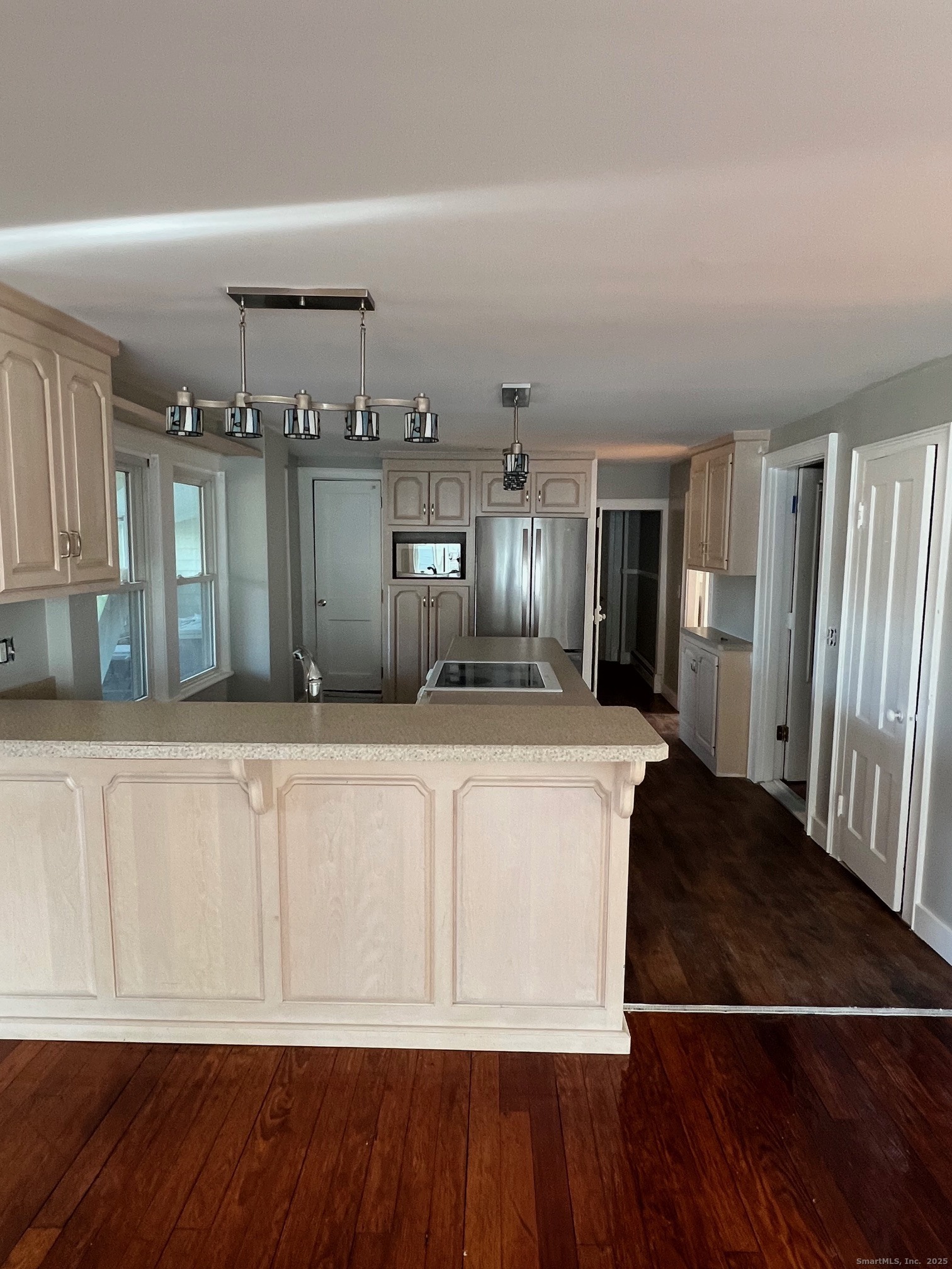 a view of a kitchen with kitchen island wooden floor and refrigerator