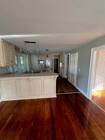 a kitchen with a wooden floor and a view of living room