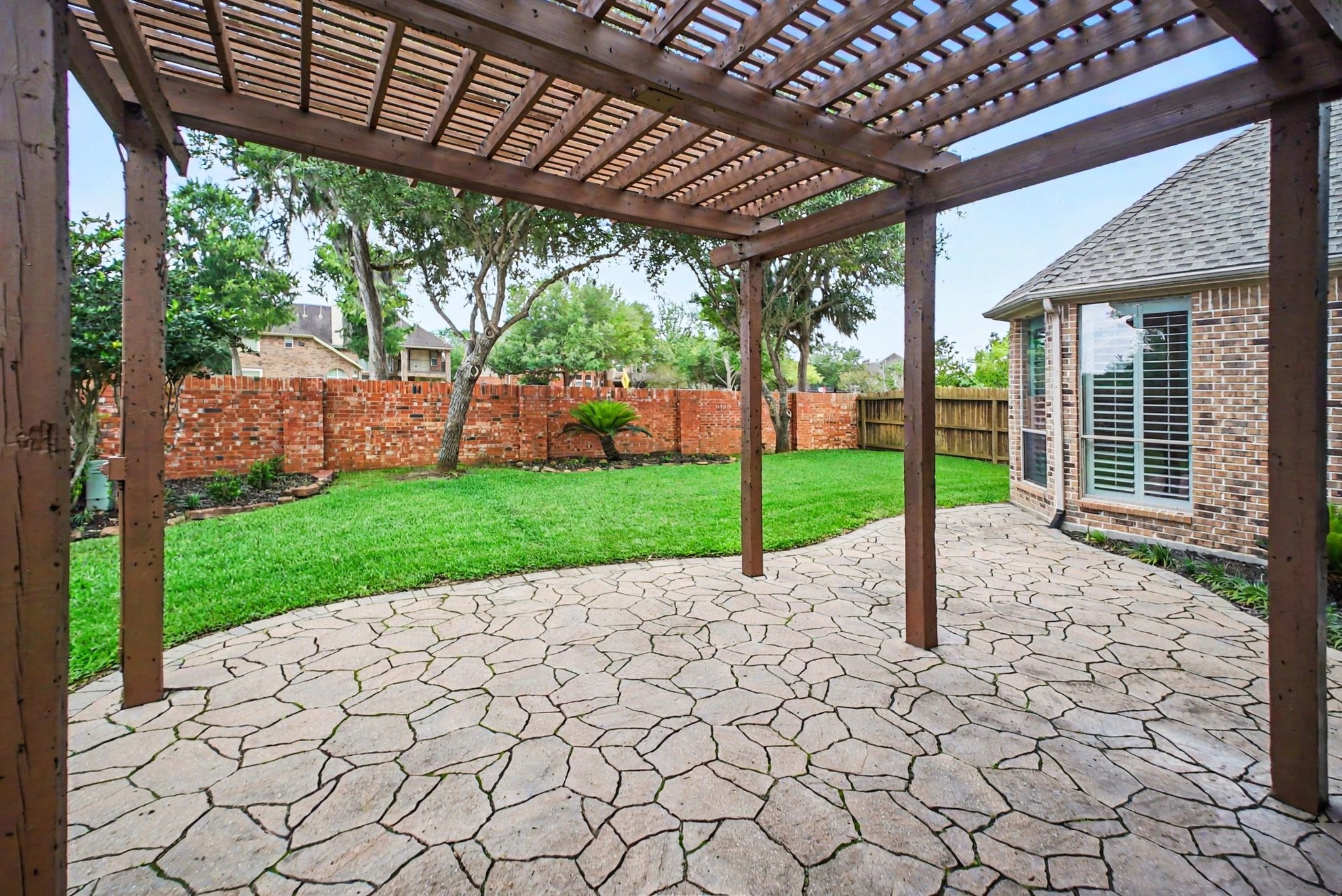8210 Thunder Ridge Way Missouri City, TX 77459 - Photo 19 of 42 Charming patio with a pergola just outside the back door, perfect for outdoor dining or lounging. Enjoy the beautifully landscaped backyard with a classic brick wall for added privacy.