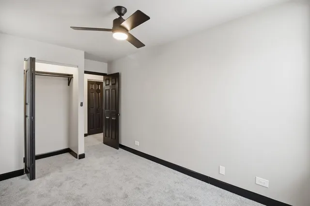 an empty room with a ceiling fan and window