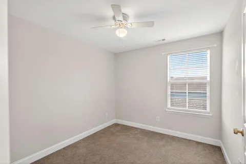 an empty room with a window and a fan