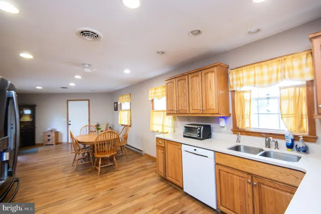 a kitchen with stainless steel appliances granite countertop wooden cabinets a dining table and chairs with wooden floor
