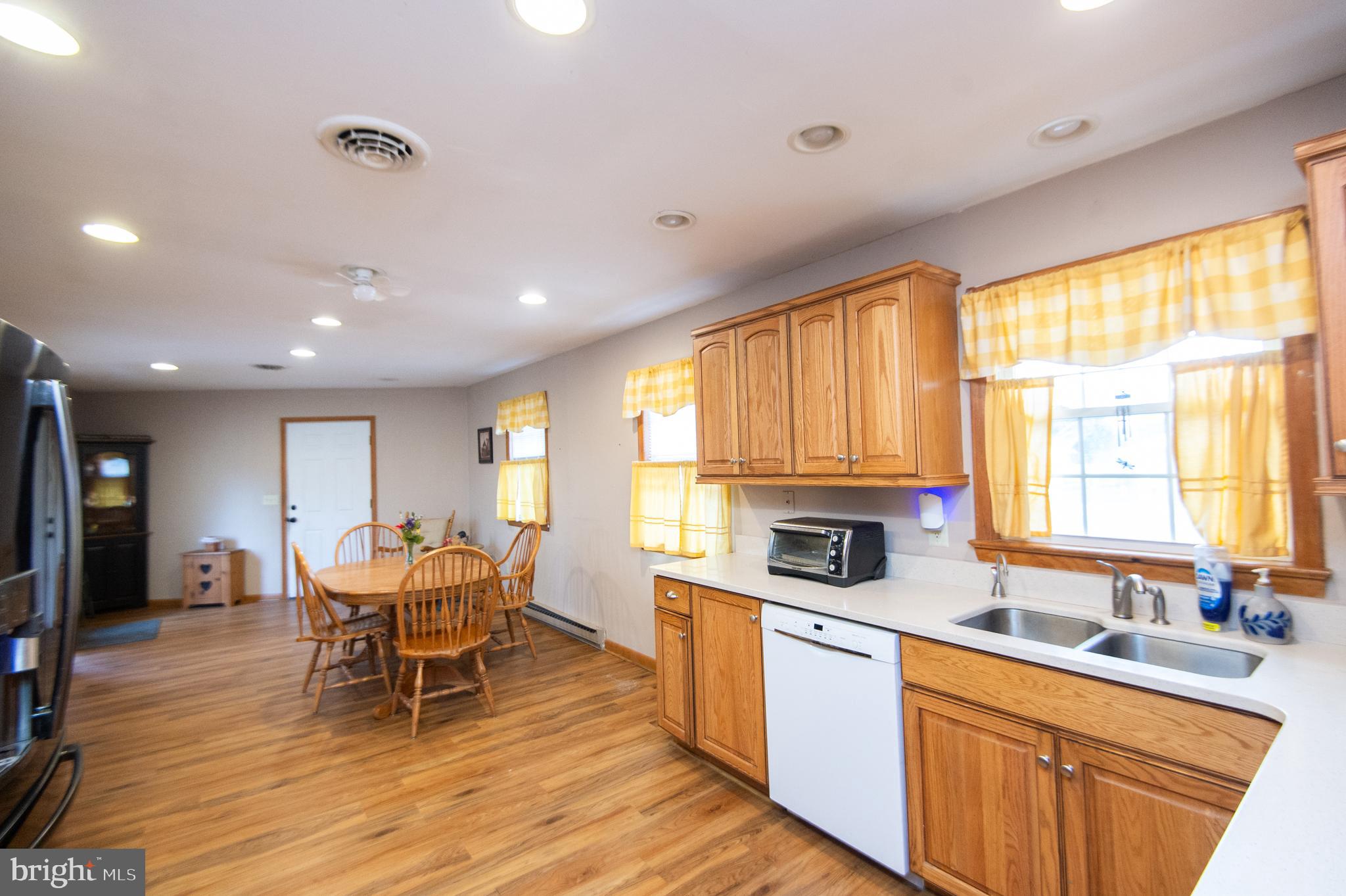 6132 Palmer Mill Road Hurlock, MD 21643 - Photo 5 of 37 a kitchen with stainless steel appliances granite countertop wooden cabinets a dining table and chairs with wooden floor