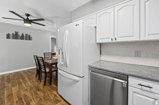 5896 South 3950th Street West Roy, UT 84067 - Photo 7 of 29 Kitchen with white cabinetry, stainless steel dishwasher, dark wood-style floors, ceiling fan, and a textured ceiling