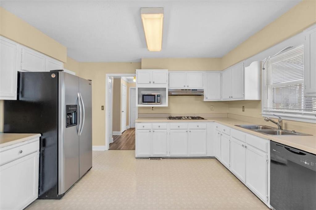 783 Pine Ridge Drive Stone Mountain, GA 30087 - Photo 14 of 32 a kitchen with kitchen island granite countertop a refrigerator sink and white cabinets