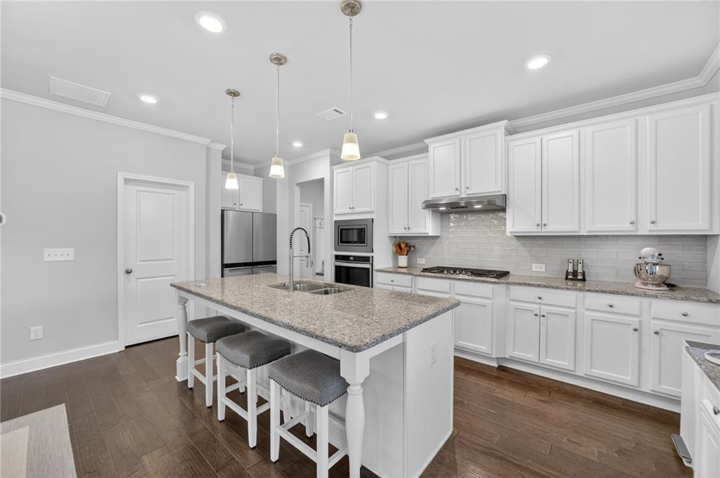 3586 Andover Way Buford, GA 30519 - Photo 14 of 63 a kitchen with stainless steel appliances granite countertop a stove a sink a refrigerator and white cabinets with wooden floor
