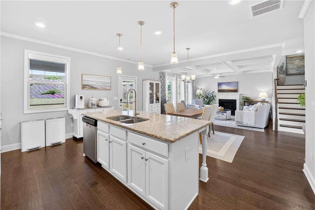 3586 Andover Way Buford, GA 30519 - Photo 16 of 63 a kitchen with stainless steel appliances kitchen island granite countertop a stove a sink a refrigerator and a dining table with wooden floor
