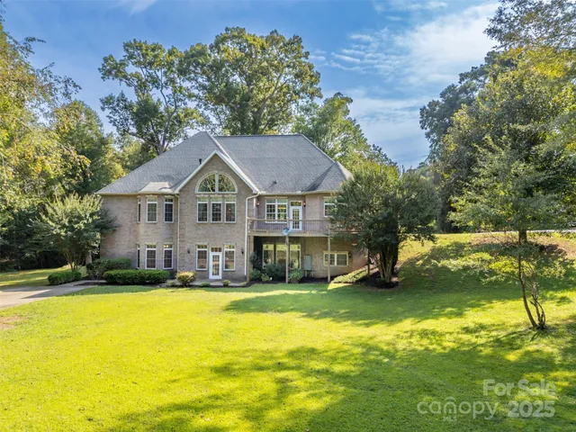 a view of a house with a yard and a large tree